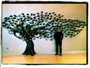 Artist Floyd Elzinga with his Sculptural donor tree with metal leaves printed with contributors name.