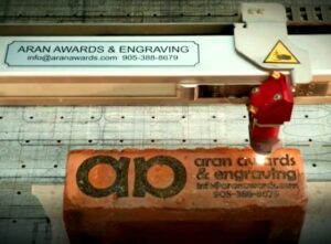 laser engraving red clay brick with Aran Awards & Engraving Logo
